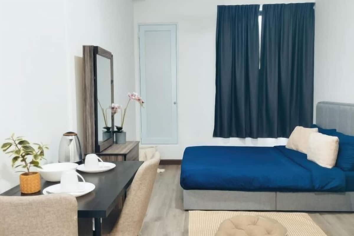 A modern bedroom with a bed, a desk, a chair, a mirror, and a window with curtains.