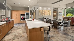 A modern kitchen with a central island, stainless steel appliances, and a dining area with a view.