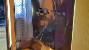 Une salle de bain avec un rideau de douche, un miroir et un porte-serviettes.