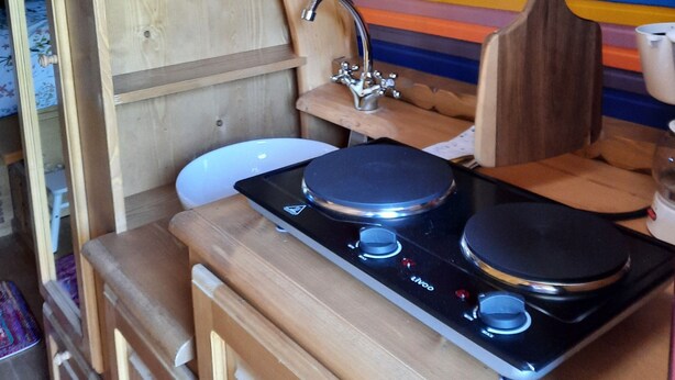 Une cuisine de taille réduite, dotée d’un plan de travail en bois, d’une cuisinière et d’un évier.