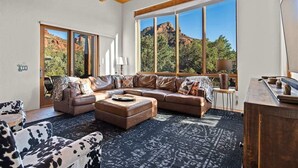 A spacious living room with a large window, a ceiling fan, and a leather sofa.