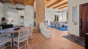 A spacious living area with a fireplace, wooden ceiling beams, and a stone wall.