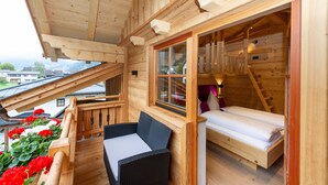 Een houten vakantiehuisje met een balkon, een bed en een raam.