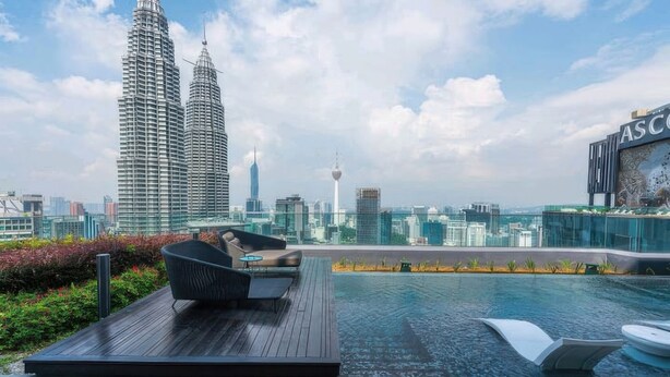 A rooftop pool area with a view of the Petronas Towers and a modern building with a sign. - Star Luxury Suites KLCC (Kuala Lumpur)