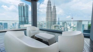 A balcony with white furniture and a cityscape view including the Petronas Towers. - Star Luxury Suites KLCC (Kuala Lumpur)