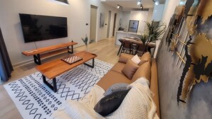 A modern living room with a flat-screen TV, wooden bench, patterned rug, and a sofa with cushions. - Star Luxury Suites KLCC (Kuala Lumpur)
