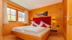 Ein Schlafzimmer mit Holzwänden, einem Bett, einem Fenster mit Vorhängen, einer Wandlampe und einem Gemälde.