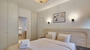 A modern bedroom with a large bed, a bedside table, a wardrobe, and a wall-mounted light fixture. - Superb Apartment in the Heart of Paris (Paris)