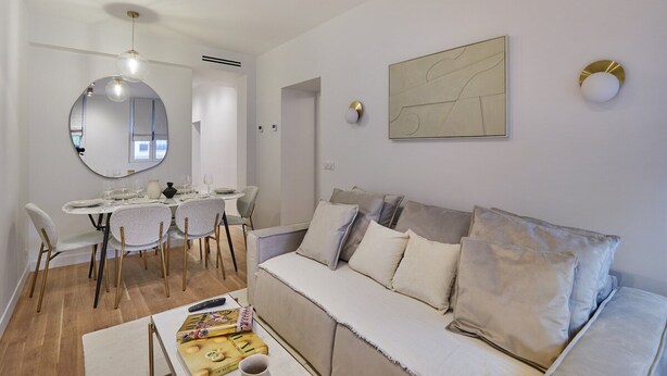 A modern living room with a dining area, a sofa, and a round mirror. - Superb Apartment in the Heart of Paris (Paris)