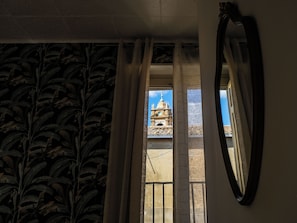 Una habitación con vistas a un edificio con una cúpula y un campanario, visible a través de cortinas translúcidas.