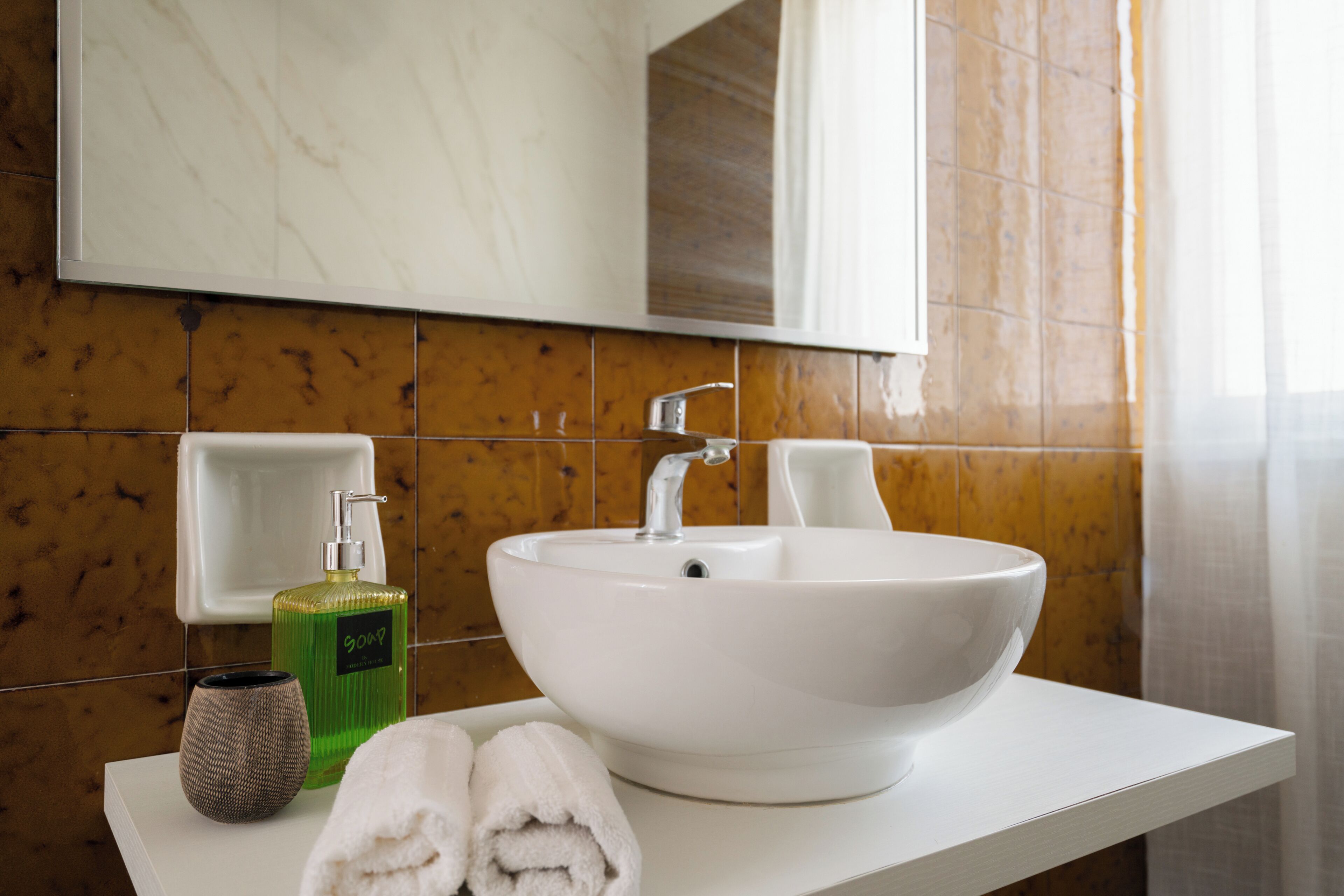 Une salle de bain avec un lavabo blanc, un miroir au-dessus et une serviette posée sur le comptoir.