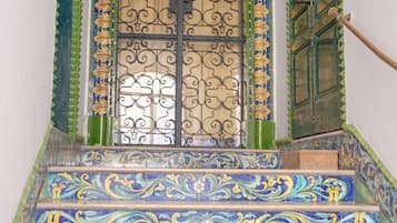A staircase with ornate blue and yellow tiles leading to a door with a decorative metal gate.