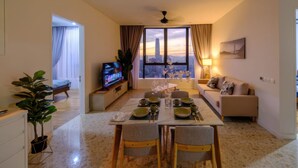 A modern living room with a dining area, a TV, and a city view. - Pavilion Ceylon Hill Suites Apartments KL (Kuala Lumpur)