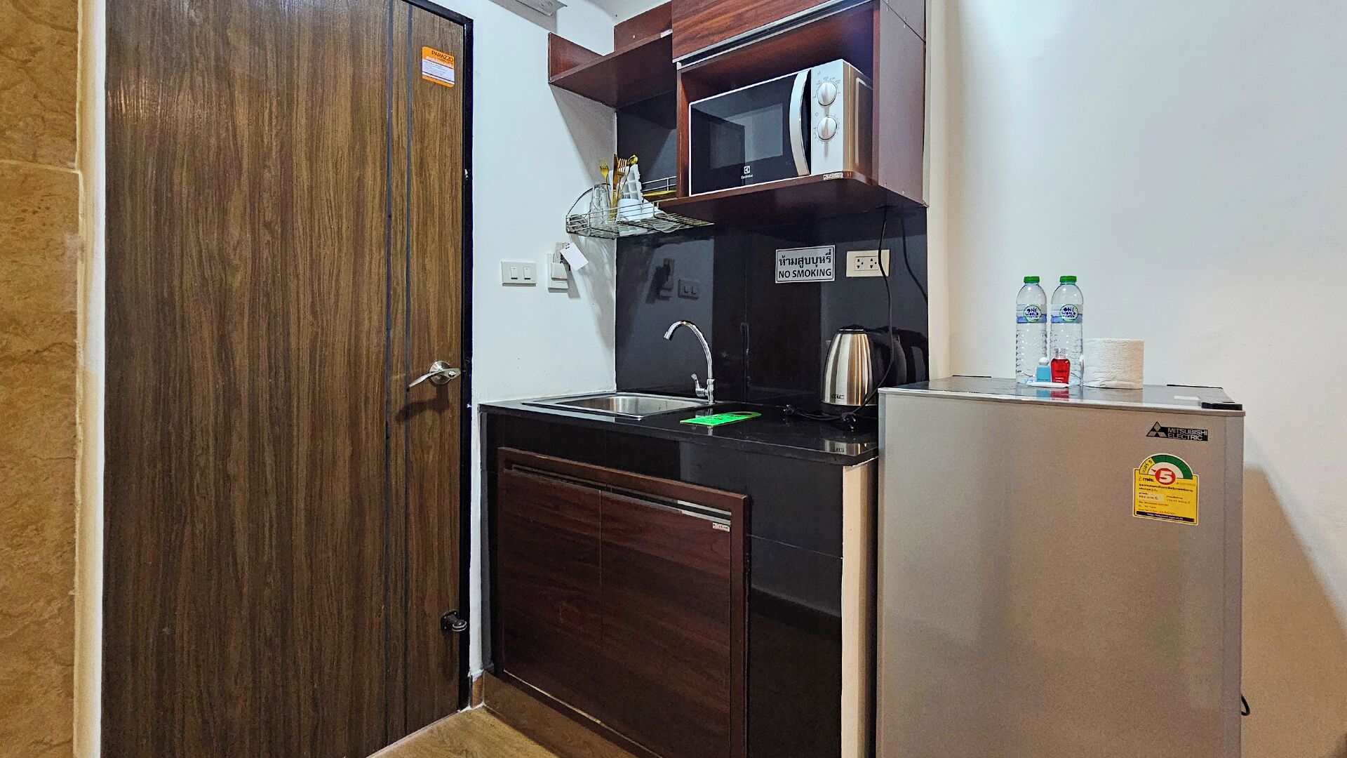 A compact kitchen with a refrigerator, microwave, sink, and cabinets.