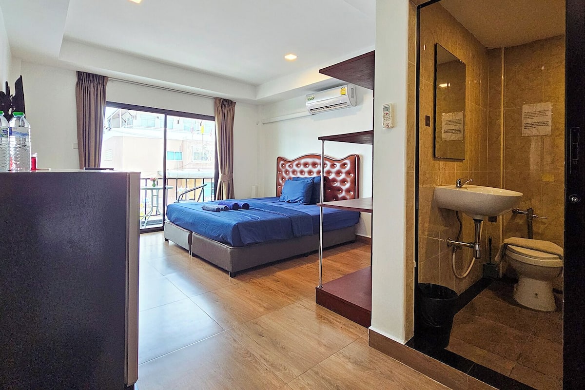 A hotel room with a bed, a desk, a balcony, and a bathroom.