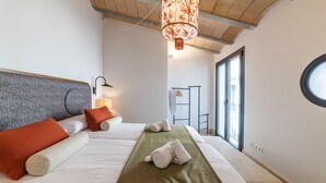 Ein Hotelzimmer mit zwei Betten, einem grünen Bettüberzug, weißer Bettwäsche und einem großen Fenster mit Blick.