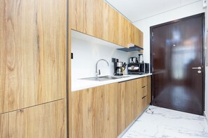 A modern kitchen with wooden cabinets, a stainless steel sink, and a dark-colored refrigerator. - Bloomfields Fabulous STU In Al Maryah  (Abu Dhabi)
