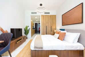 A modern hotel room with a bed, TV, and a view of the kitchen. - Bloomfields Fabulous STU In Al Maryah  (Abu Dhabi)