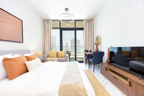 A hotel room with a large bed, a TV, a dining area, and a view of the cityscape. - Bloomfields Fabulous STU In Al Maryah  (Abu Dhabi)