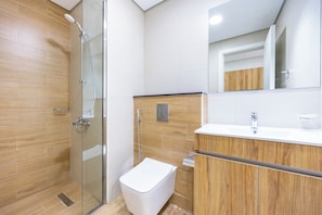 A modern bathroom with a glass-enclosed shower, a wooden vanity, and a white toilet. - Bloomfields Fabulous STU In Al Maryah  (Abu Dhabi)
