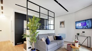 Un salon moderne avec un canapé gris, une table basse en verre et une plante en pot.