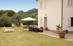 Un patio con mobiliario exterior, una mesa y sillas, y una sombrilla blanca.