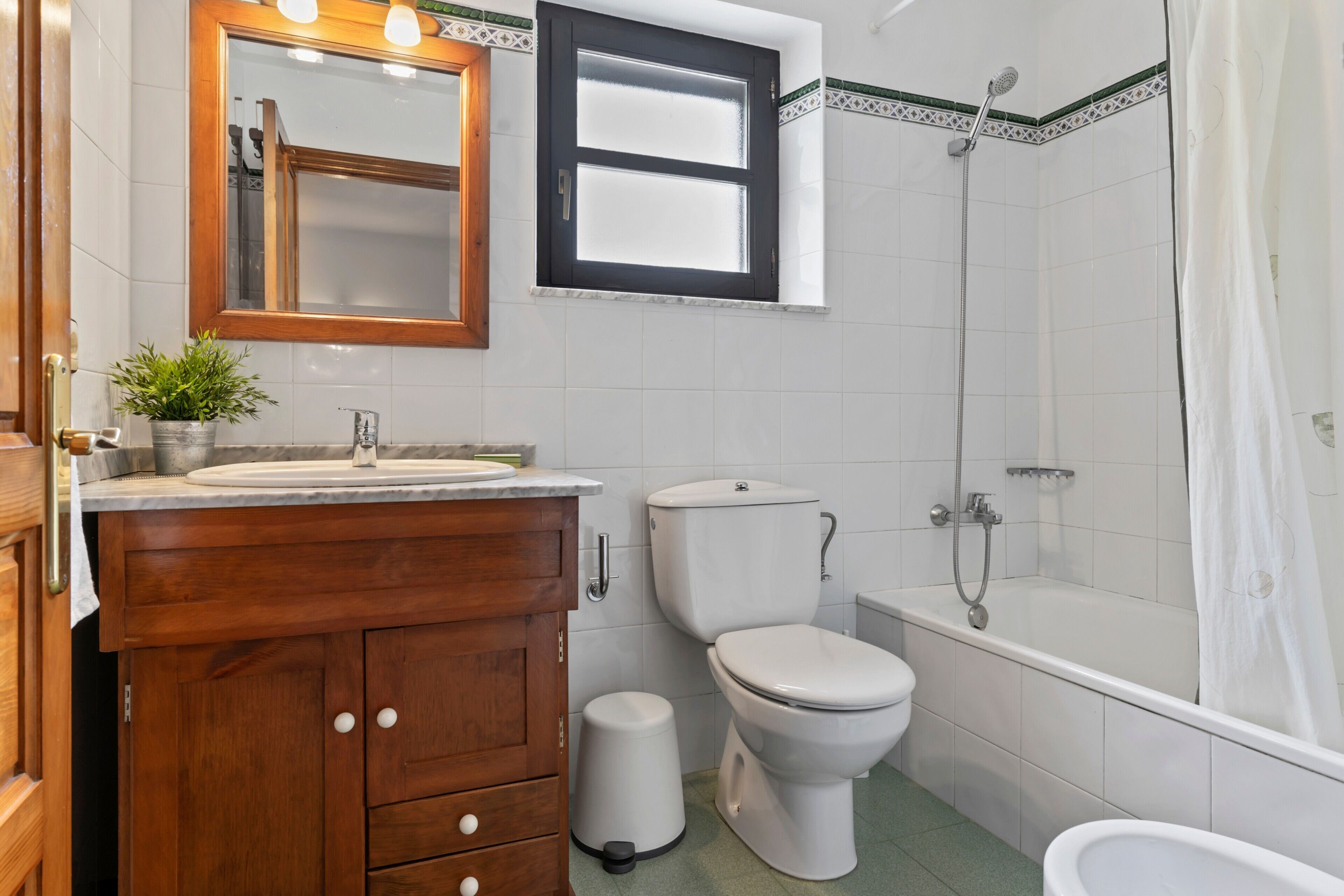 Een badkamer met een houten wastafel, toilet, bad en douche.
