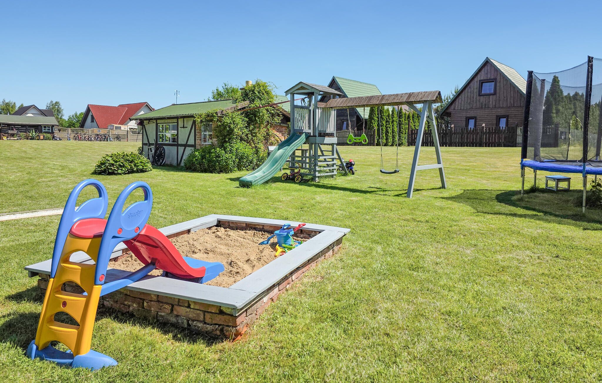 Une aire de jeux avec un toboggan, des balançoires et un bac à sable.