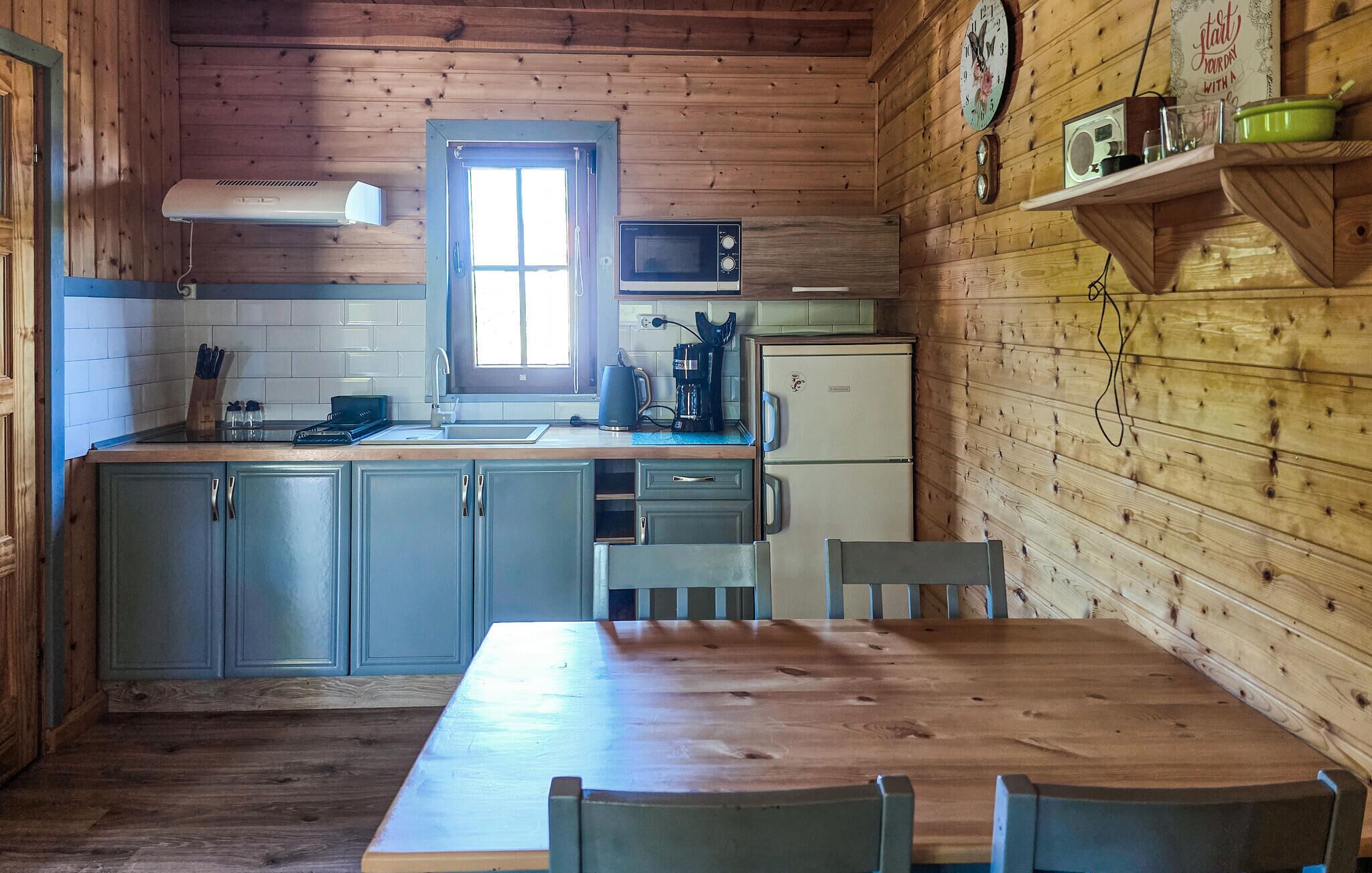 Cocina de estilo cabaña con ventana, un lavamanos, estufa y refrigerador.