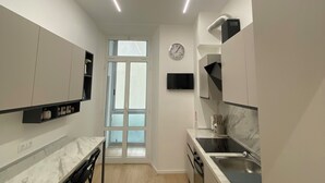 Une cuisine moderne dotée d’un plan de travail en marbre, de meubles noirs et d’un four encastré.