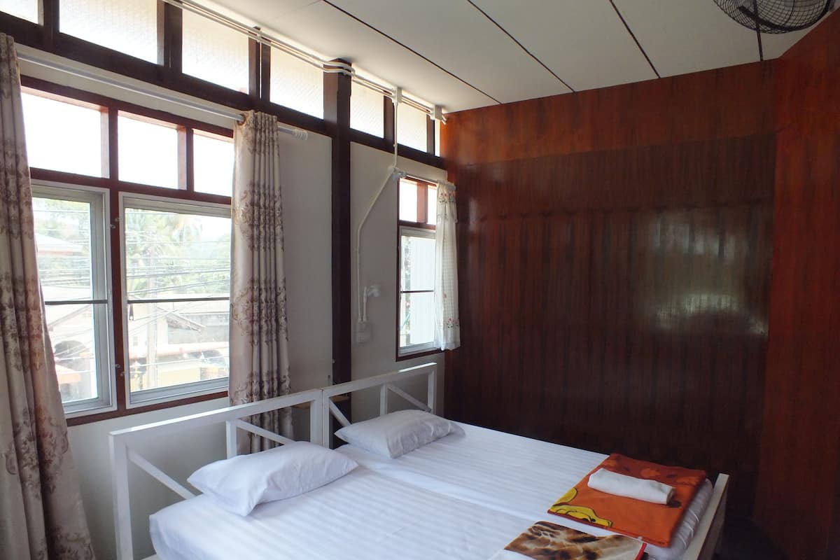 Una cama doble con ropa de cama blanca, un cabecero de madera y una ventana con cortinas.