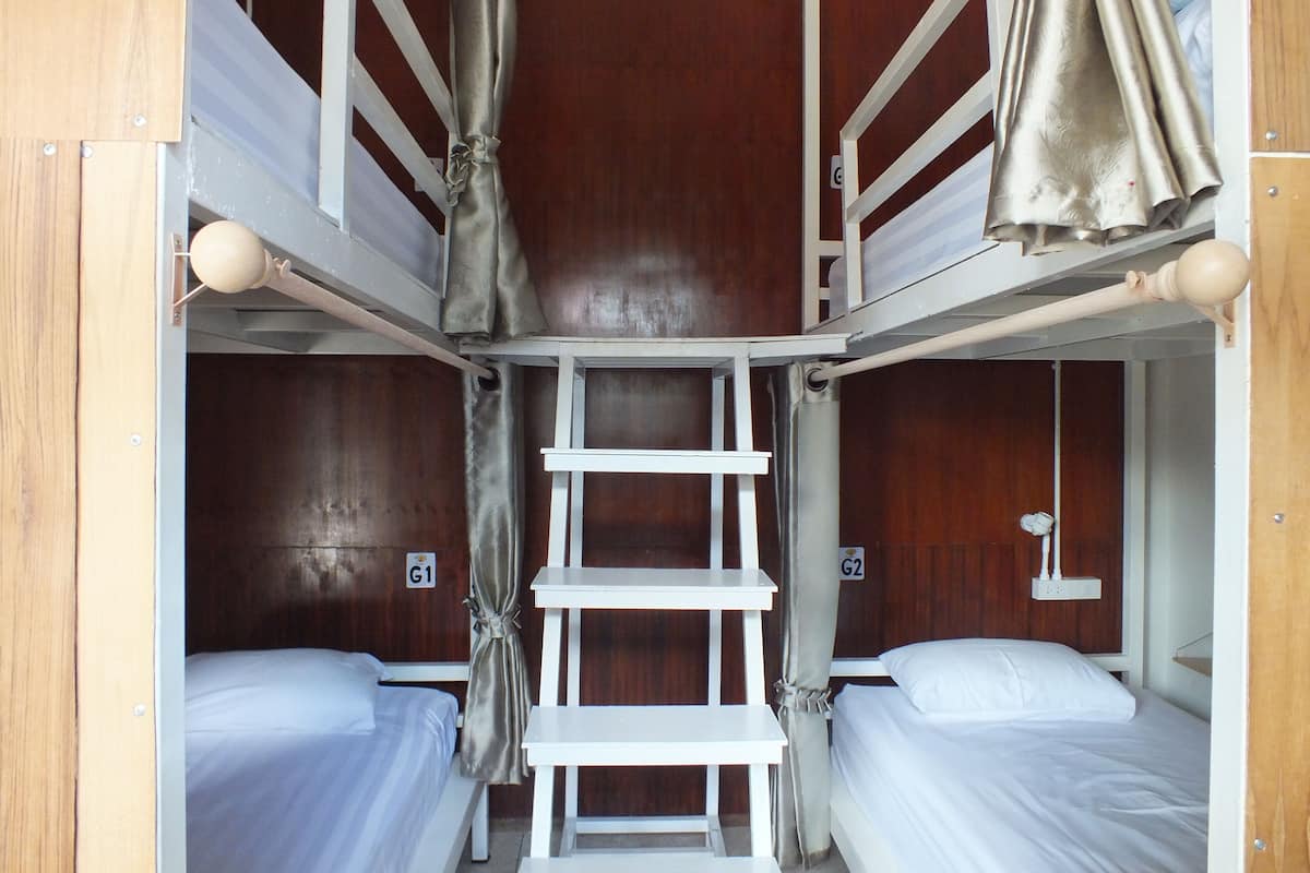 Dormitorio con literas, dos camas, una escalera y una mesita.