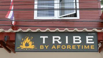 A building with a sign that reads "TRIBE BY AFORETIME" featuring a fire graphic.