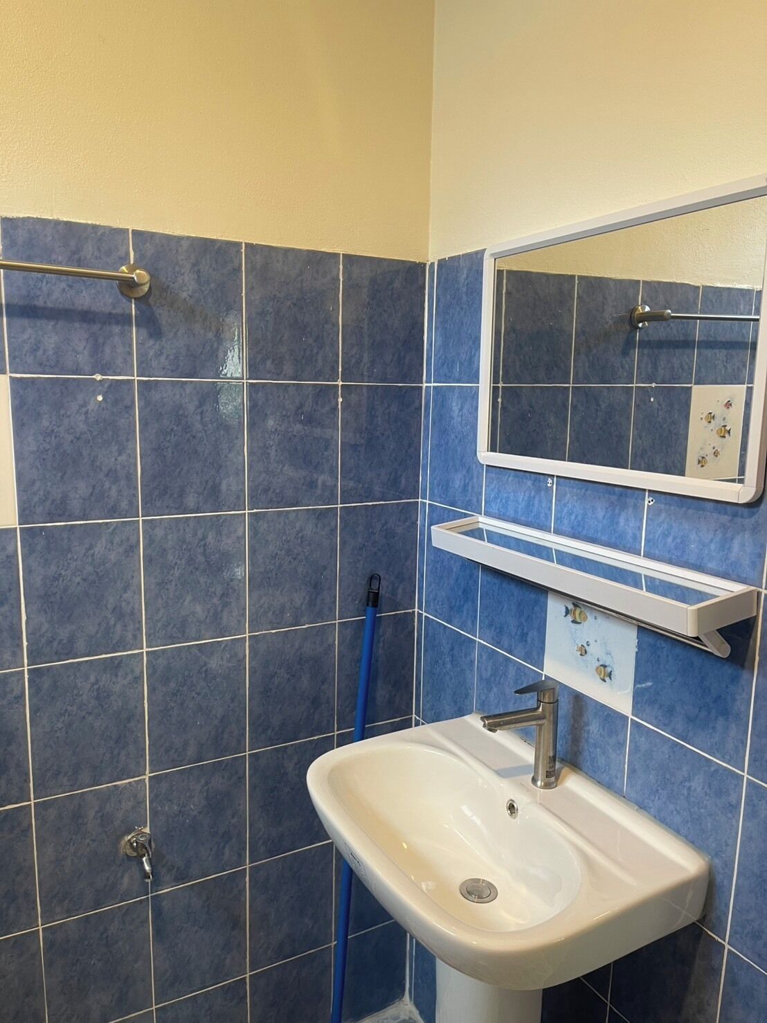 A bathroom with a sink, mirror, and blue-tiled walls.
