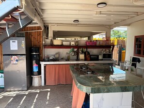Cocina compacta con refrigerador, estufa y diversos utensilios de cocina.