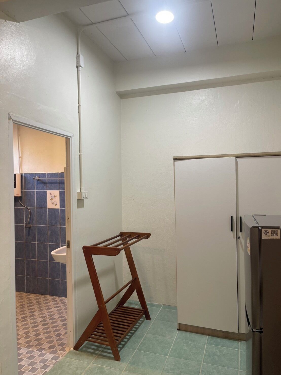 A bathroom with a wooden drying rack, a sink, and a refrigerator.