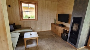 A wooden interior with a sofa, a small table, a TV, and a fireplace. - Vacation chalet with sauna and large terrace at Ferienhof Schiegl in the bay. Forest (Brennberg)