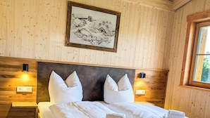 A wooden-paneled bedroom with a large bed, two bedside tables, and a framed picture on the wall. - Vacation chalet with sauna and large terrace at Ferienhof Schiegl in the bay. Forest (Brennberg)