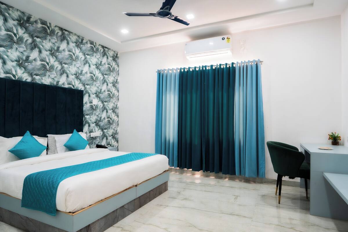 Une chambre d’hôtel équipée d’un lit, d’un bureau, d’une chaise, d’un ventilateur de plafond et d’un appareil de climatisation.