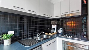 Una cocina moderna con salpicadero de azulejos negros, electrodomésticos de acero inoxidable y armarios blancos.