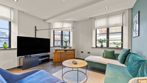A modern living room with a flat-screen TV, a sofa, a coffee table, and a dining area. - Picasso in London (london)