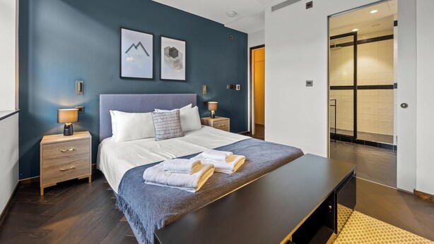 A modern hotel room with a large bed, bedside tables, a desk, and a bathroom visible through an open door. - Picasso in London (london)