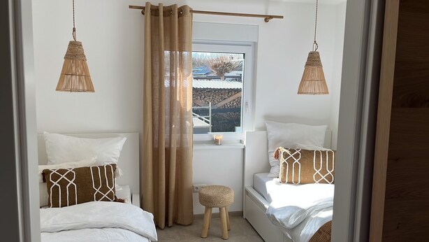 Ein Schlafzimmer mit zwei Betten, einem Fenster mit Blick und zwei Pendelleuchten.