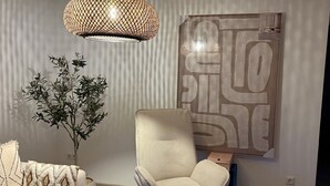 Ein modernes Wohnzimmer mit einer Couch, einem Sessel, einem Hocker und einem Couchtisch.