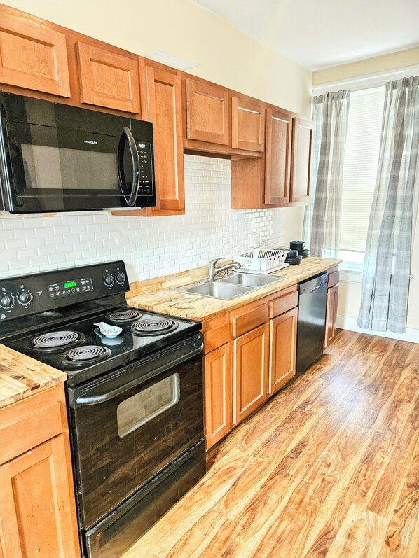 A kitchen with wooden cabinets, a black stove, a microwave, and a dishwasher.