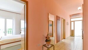 A hotel hallway with a bed, a small table with a plant, and a mirror. - Beachfront apartment Liverić 2 (Vir)