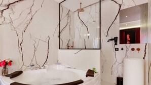Een moderne badkamer met een marmeren wand, een ruime badkuip, een spiegel en een wastafelmeubel.