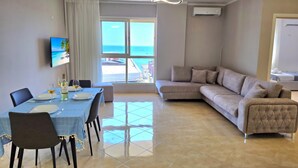 Una sala de estar moderna con comedor, un sofá y un televisor montado en la pared.