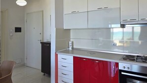 A modern kitchen with white and red cabinetry, a stainless steel range hood, and a built-in oven. - Beachfront & Sea View Apartment 102 (Durres)