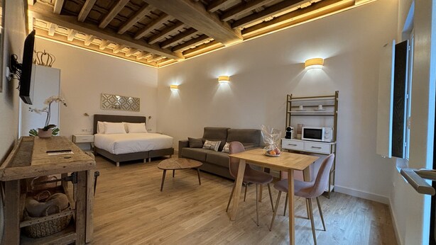 A cozy bedroom with a bed, a sofa, a dining table with chairs, and a microwave. - Mirador Del Rey (Cuenca)